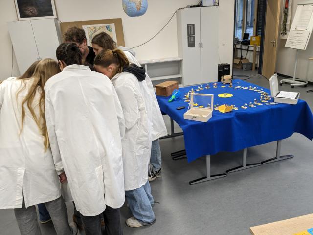 A group of students clad in laboratory coats stick together to solve a riddle. 